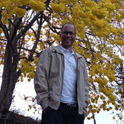 Juan Manuel de Villeros, smiling, under a tree in yellow bloom